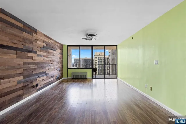 a view of an empty room with a window and wooden floor