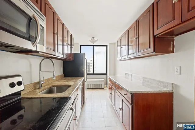 a kitchen with stainless steel appliances granite countertop a sink a stove and a refrigerator