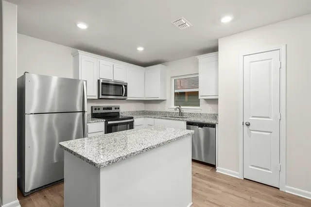 a kitchen with stainless steel appliances granite countertop a refrigerator a stove microwave and sink