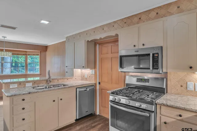 a kitchen with granite countertop a sink stove and cabinets