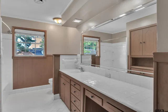 a spacious bathroom with a granite countertop sink a large mirror and a window