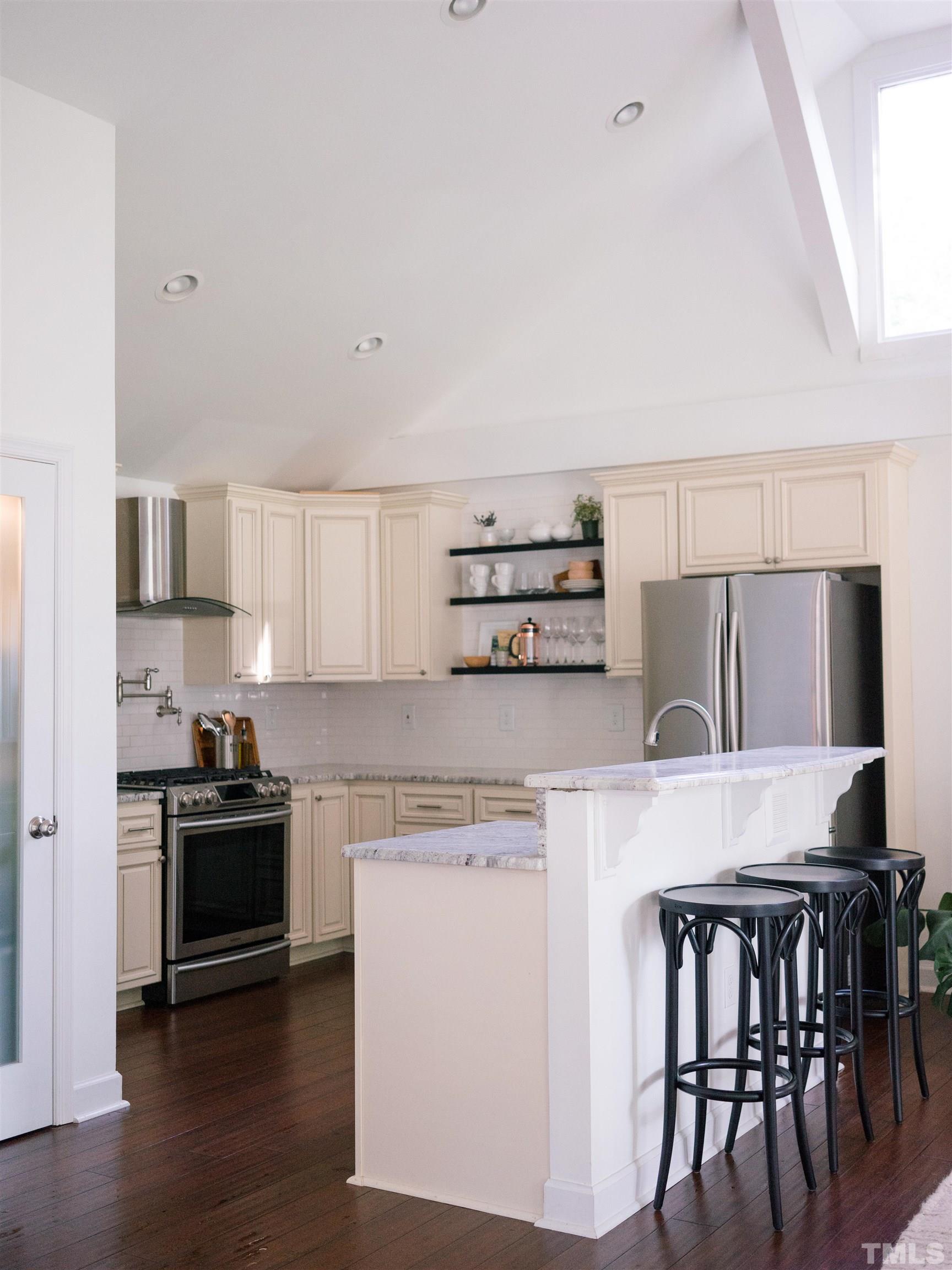 509 Freeman Street Raleigh, NC 27601 - Photo 7 of 20 a kitchen with stainless steel appliances a stove a sink a microwave a dining table and chairs