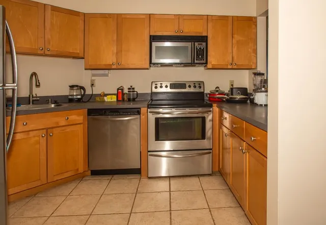 a kitchen with stainless steel appliances granite countertop a stove a sink and a microwave