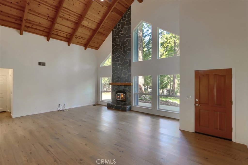 7174 Hites Cove Road Mariposa, CA 95338 - Photo 8 of 62 an empty room with wooden floor fireplace and windows