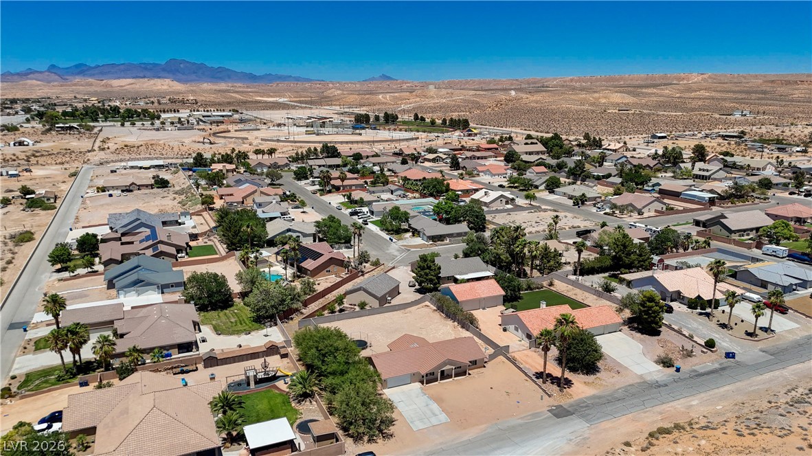 1272 Liston Avenue Logandale, NV 89021 - Photo 57 of 61 An aerial perspective reveals a vibrant neighborhood nestled against distant mountains, featuring a mix of residences and recreational spaces.