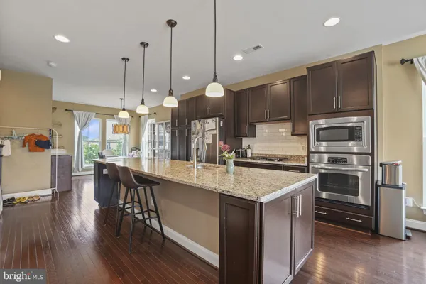 a kitchen with stainless steel appliances granite countertop a sink a stove and chairs