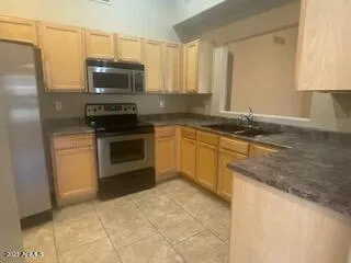 a kitchen with granite countertop a sink a stove top oven a counter space and cabinets
