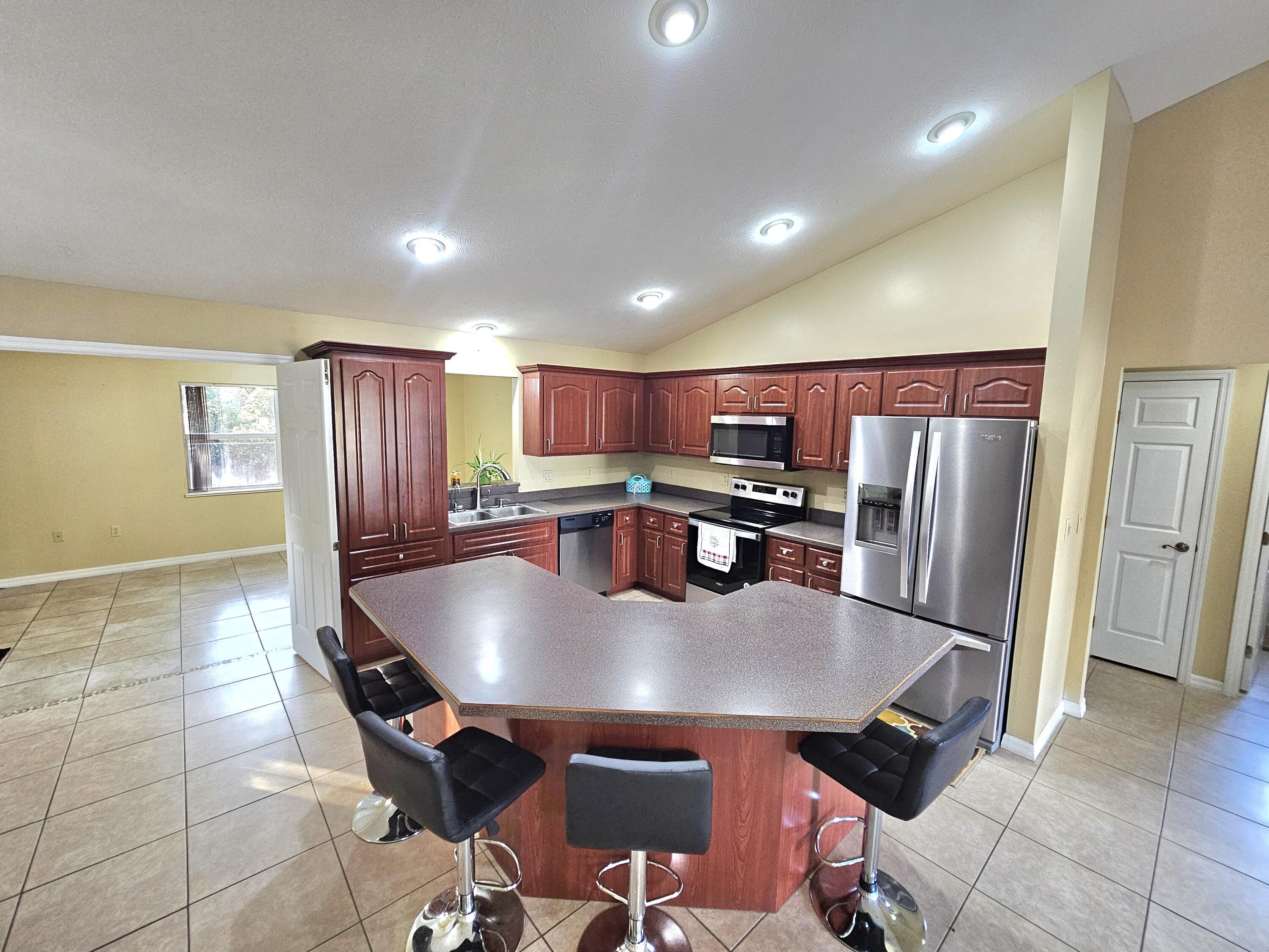 1514 Summer Road Lake Placid, FL 33852 - Photo 13 of 52 a large kitchen with stainless steel appliances a table chairs and a refrigerator