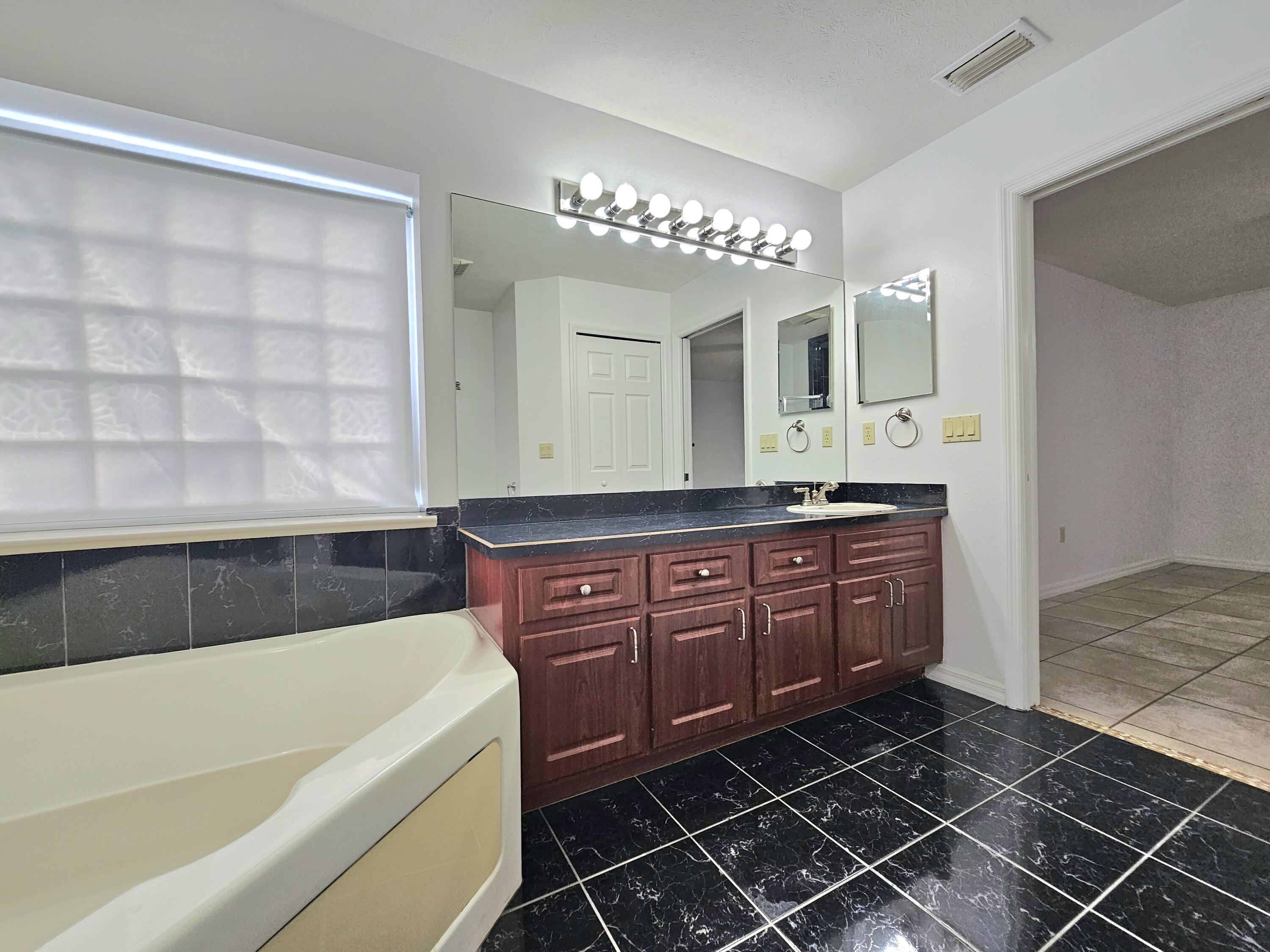 1514 Summer Road Lake Placid, FL 33852 - Photo 29 of 52 a bathroom with a granite countertop sink a mirror and bathtub