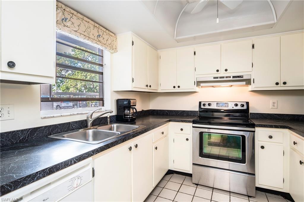 5451 Rattlesnake Hammock Road, Unit D108 Naples, FL 34113 - Photo 5 of 17 a kitchen with granite countertop white cabinets and white stainless steel appliances