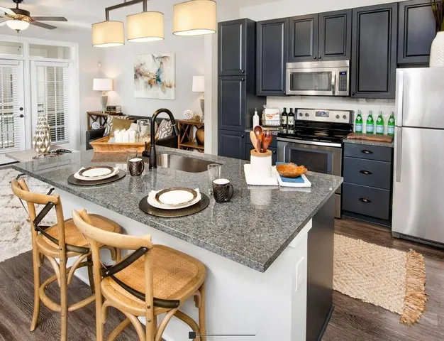 a kitchen with stainless steel appliances granite countertop a stove top oven a dining table and chairs