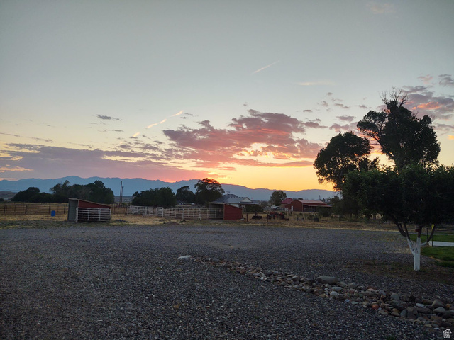 2170 Highway 357 Beaver, UT 84713 - Photo 52 of 56 Expansive gravel area with natural stone border, mature trees, and outbuildings, all framed by distant mountains