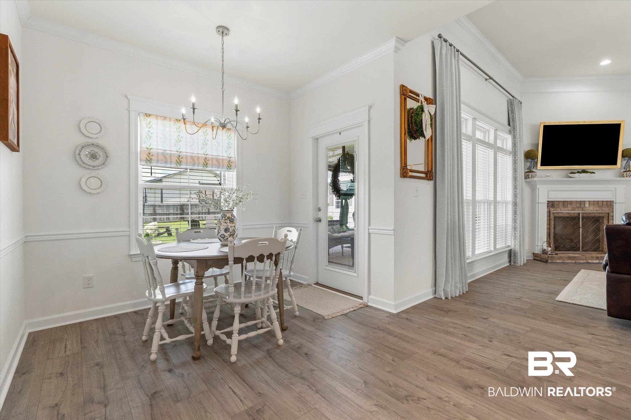 9074 Moses Way Theodore, AL 36582 - Photo 20 of 52 Open-concept living area featuring wood-finish flooring, a brick fireplace with a white mantel, and extensive window treatments