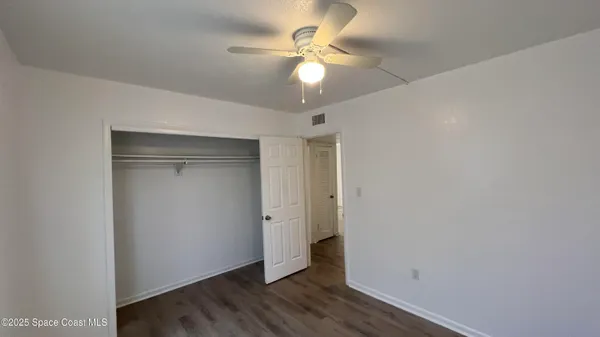 an empty room with wooden floor and fan
