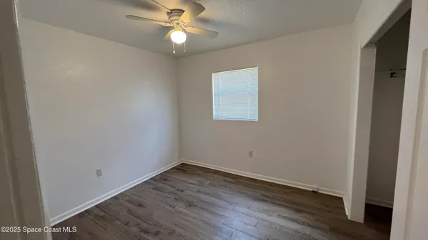 an empty room with wooden floor and ceiling fan