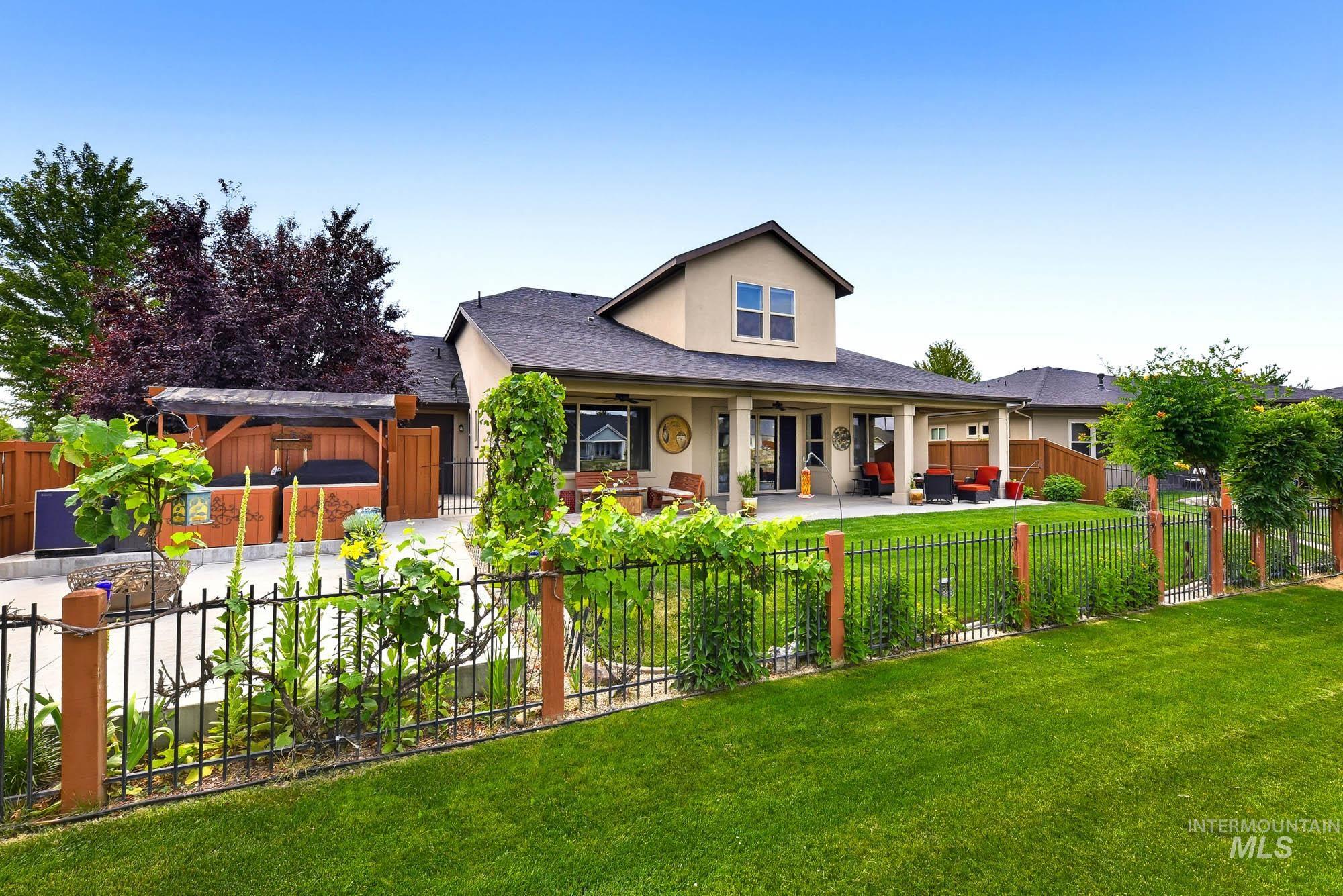 220 South Wildgrass Way Star, ID 83669 - Photo 43 of 50 Paved patio area featuring a mature tree with red foliage, a brown panel garage door, a stucco exterior wall, and a wooden fence