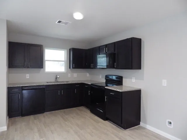 a kitchen with sink a microwave and cabinets