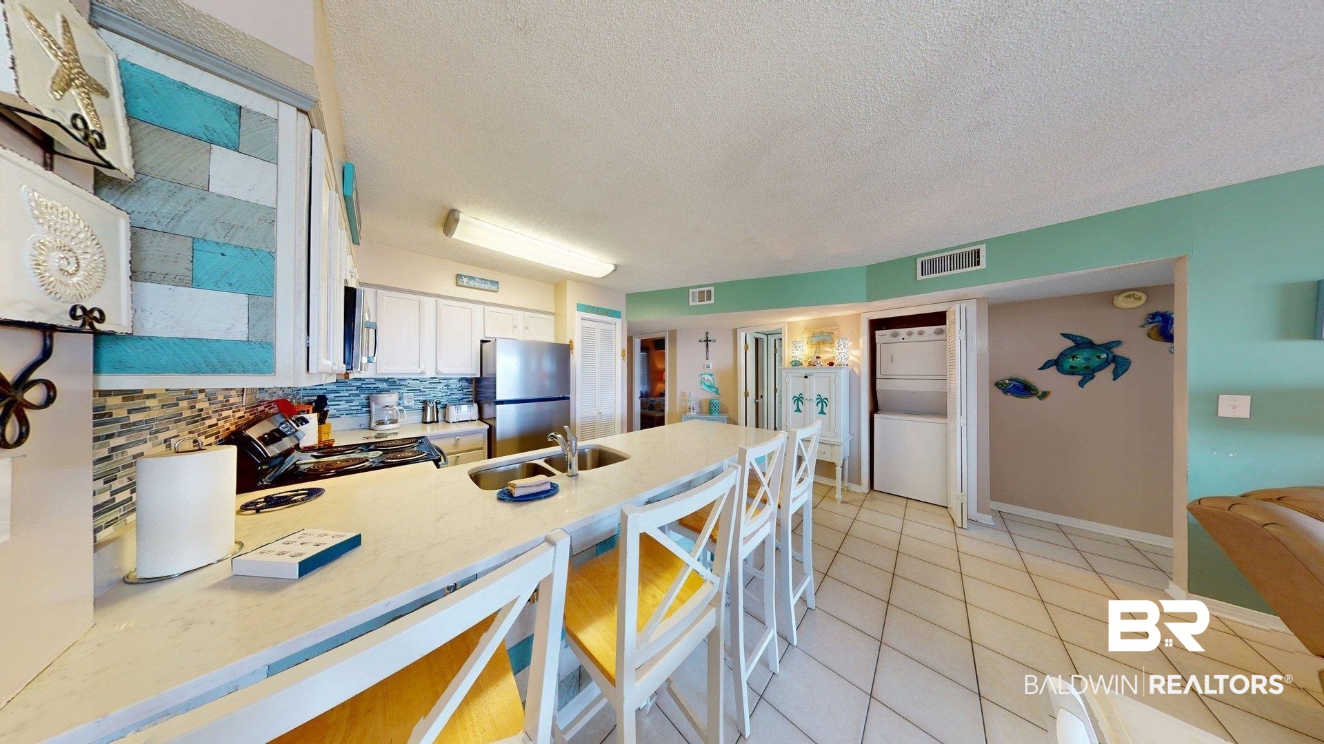 645 Plantation Road, Unit 6503 Gulf Shores, AL 36542 - Photo 23 of 53 Kitchen with a textured ceiling, a peninsula, tasteful backsplash, light stone counters, and light tile patterned flooring