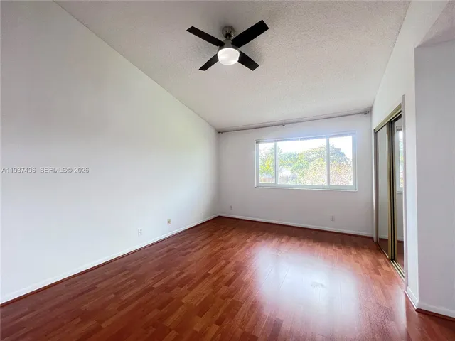 an empty room with wooden floor and a ceiling fan