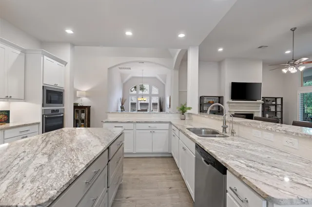 a large kitchen with granite countertop a large counter top sink appliances and cabinets