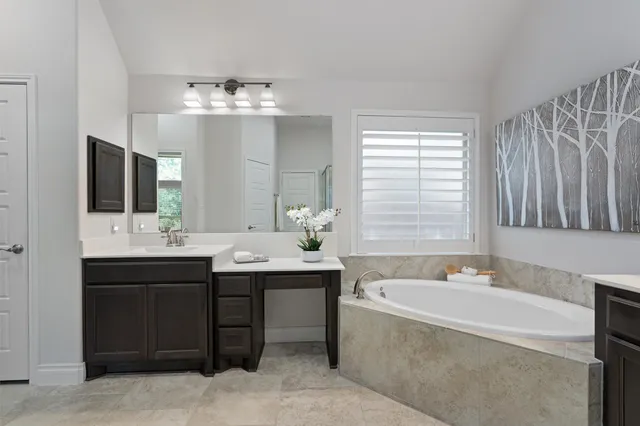 a bathroom with a bathtub double sink and mirror