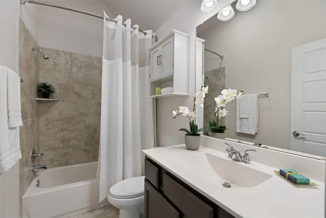 a bathroom with a bathtub shower sink mirror and toilet
