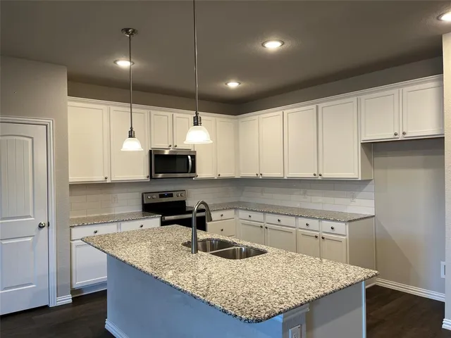 a kitchen with kitchen island granite countertop a sink a counter top space stainless steel appliances and cabinets