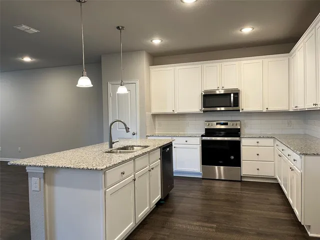 a kitchen with stainless steel appliances granite countertop a sink a stove and a wooden floors