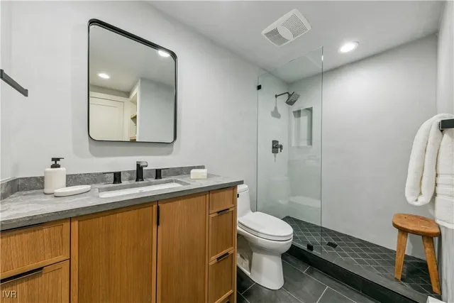 a bathroom with a granite countertop sink toilet a mirror a vanity and shower