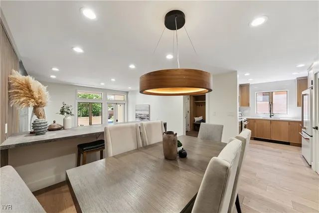 a kitchen with stainless steel appliances granite countertop a dining table chairs and white cabinets