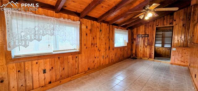 11785 Milam Road Colorado Springs, CO 80908 - Photo 31 of 44 Tiled empty room featuring wooden walls, wood ceiling, and a ceiling fan