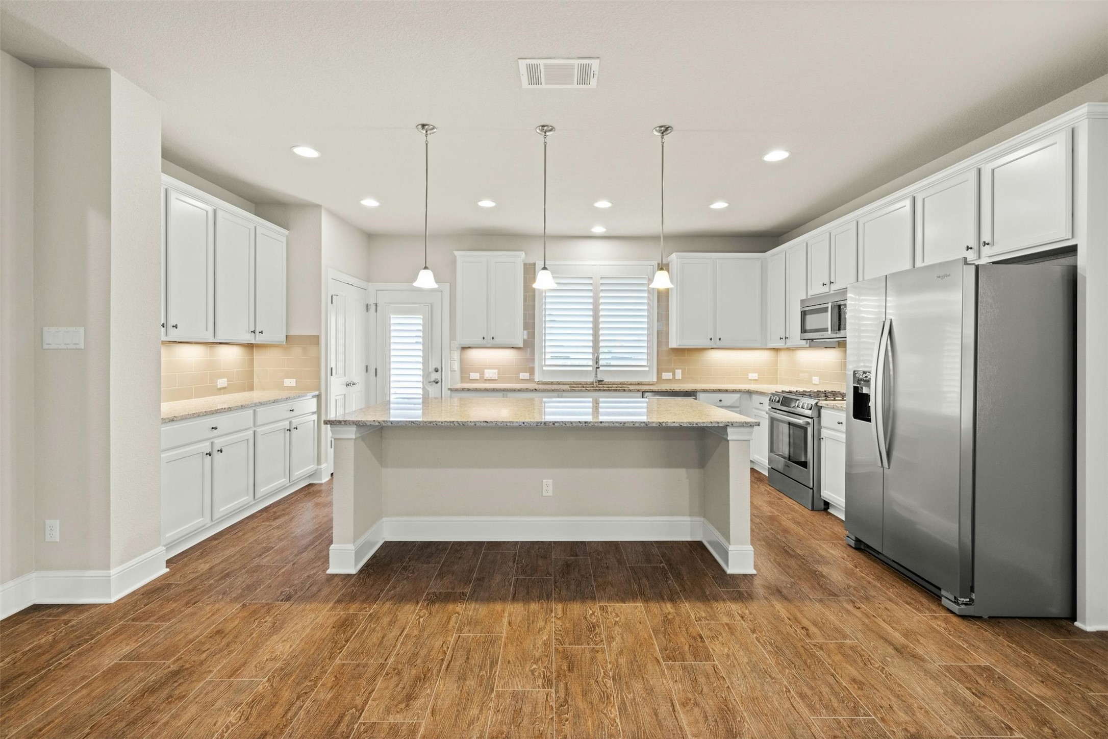a kitchen with kitchen island white cabinets and stainless steel appliances