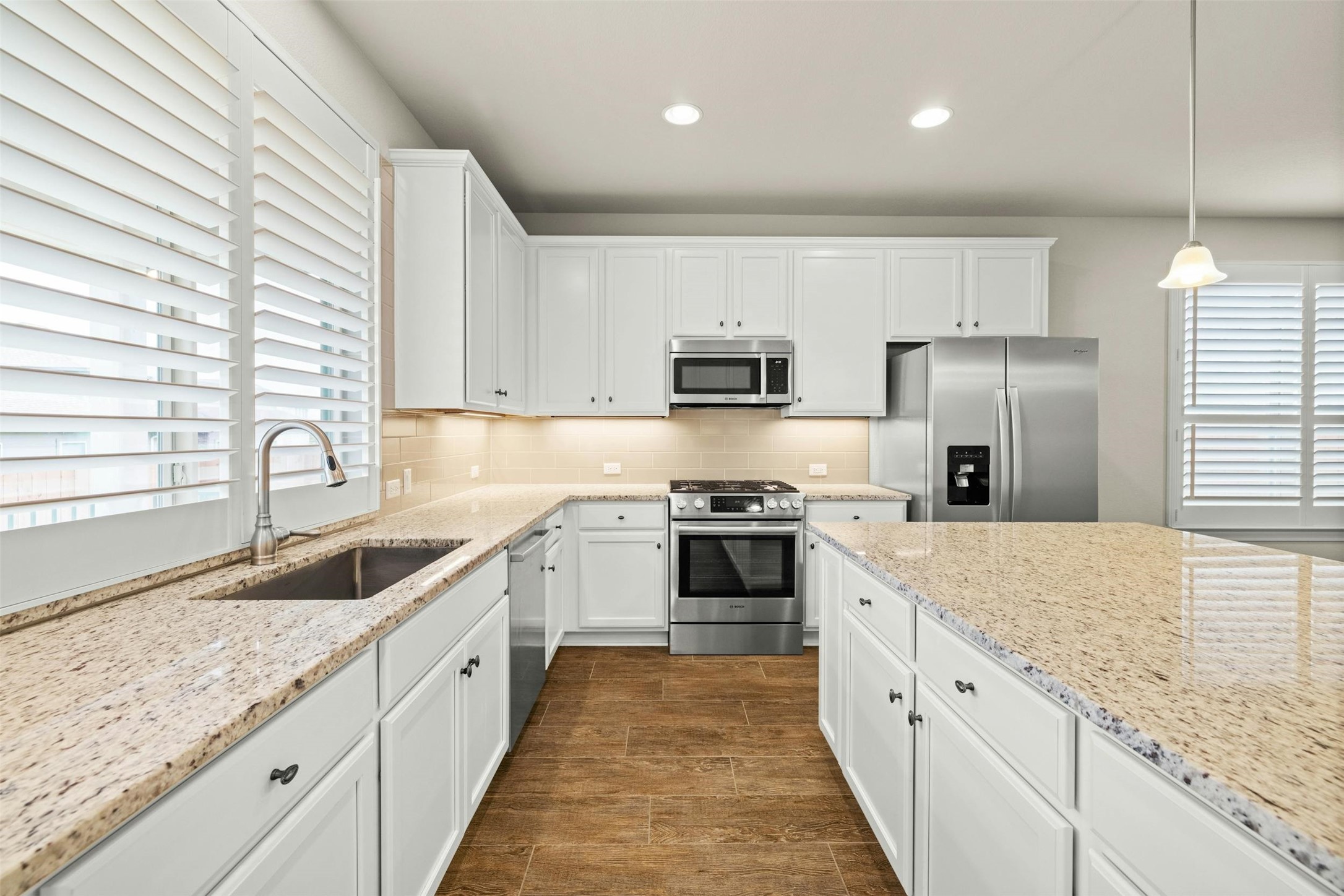 316 Crossvine Trail Georgetown, TX 78626 - Photo 17 of 37 a large kitchen with granite countertop a sink and a stove top oven with wooden floor