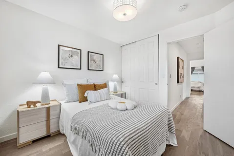a bedroom with bed and a lamp on dresser