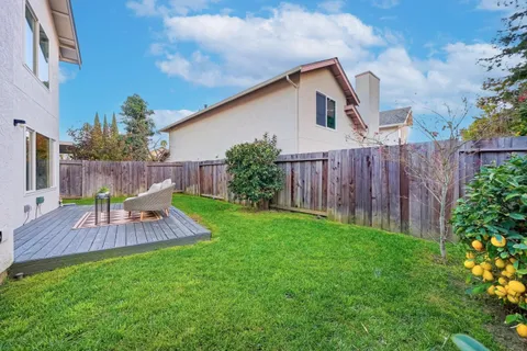 a view of a backyard with table and chairs potted plants and wooden fence