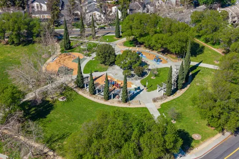 an aerial view of residential houses with outdoor space and trees