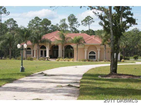 9 Remington Road Ormond Beach, FL 32174 - Photo 2 of 22 a front view of a house with a garden and trees