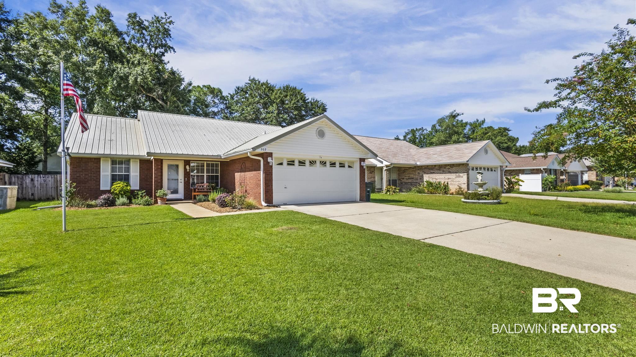302 Cluster Street Foley, AL 36535 - Photo 3 of 28 Ranch-style house featuring an attached garage, driveway, brick siding, and a metal roof