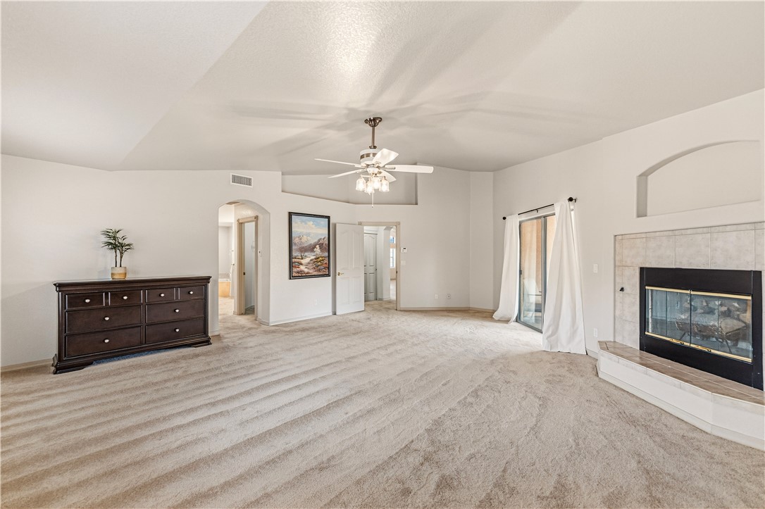 2940 Mountain Trail Road Kingman, AZ 86401 - Photo 31 of 53 Spacious interior room with light-colored carpeting, a ceiling fan, and a fireplace with a tiled surround