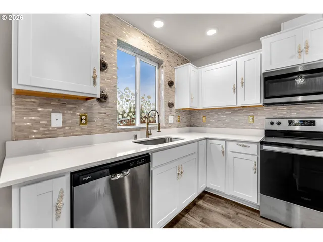 a kitchen with stainless steel appliances kitchen island granite countertop a stove top oven a sink and a refrigerator