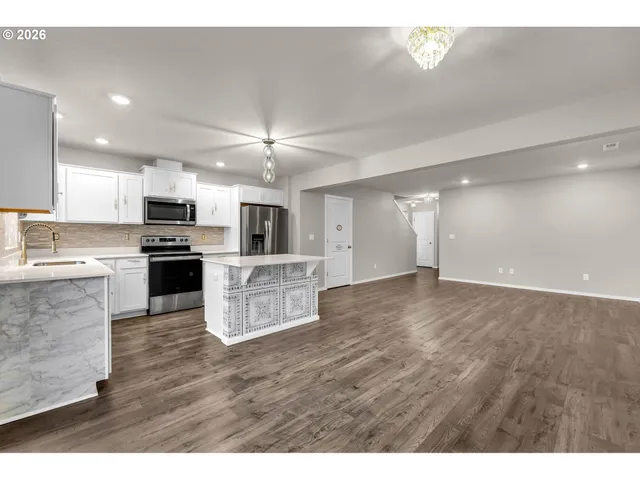 a kitchen with stainless steel appliances white cabinets a stove top oven a sink and dishwasher