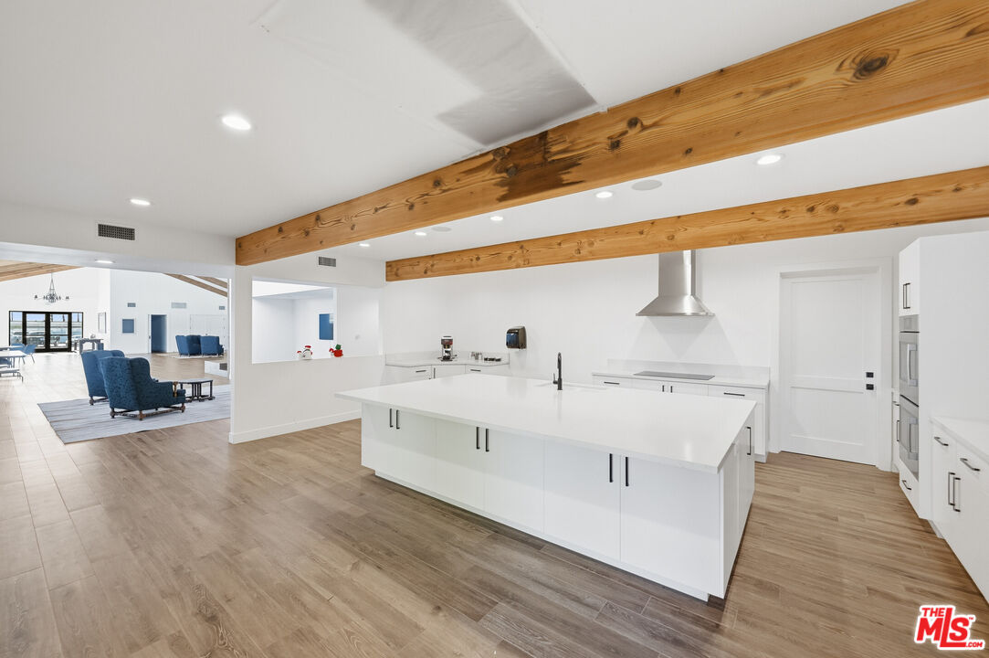 29500 Heathercliff Road, Unit 170 Malibu, CA 90265 - Photo 35 of 38 a large white room with kitchen view and wooden floor