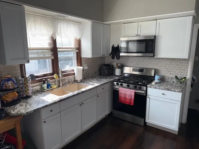 a kitchen with stainless steel appliances granite countertop a sink a stove and a microwave