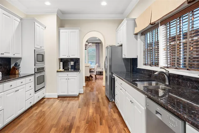 a large white kitchen with granite countertop a stove top oven a sink a counter space and cabinets