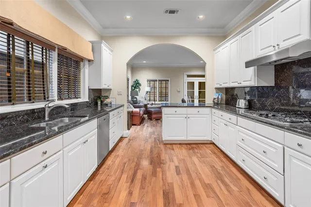 a large kitchen with granite countertop a large counter top space a sink stainless steel appliances and cabinets
