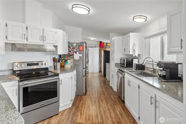 a kitchen with kitchen island wooden floors appliances and cabinets