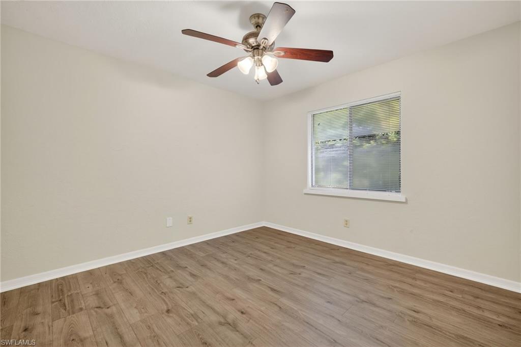 18294 Lee Road Fort Myers, FL 33967 - Photo 25 of 37 an empty room with wooden floor chandelier fan and windows
