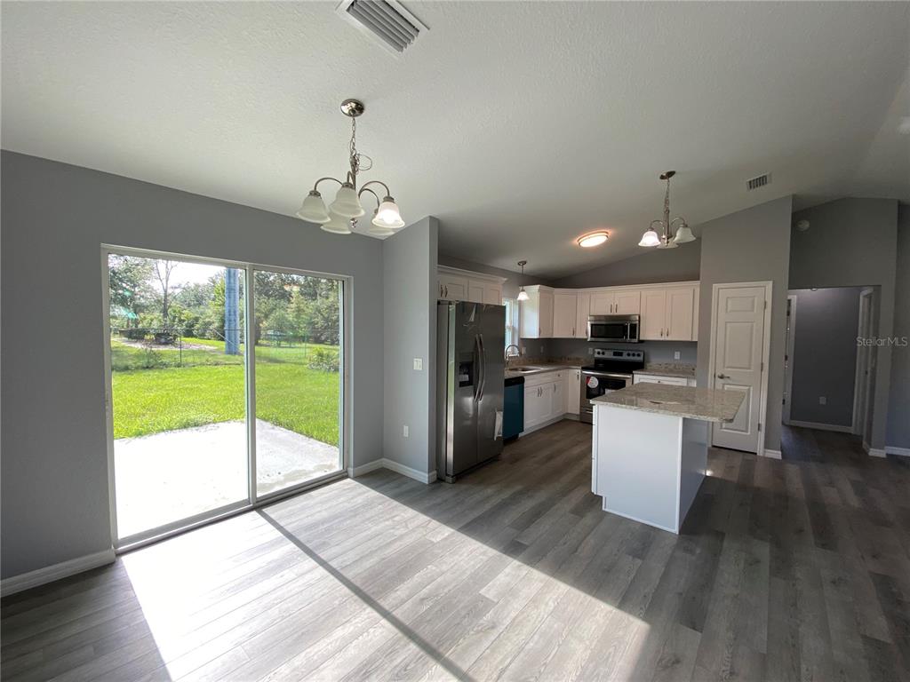 2827 Southwest 140th Loop Ocala, FL 34473 - Photo 12 of 29 a living room with stainless steel appliances kitchen island granite countertop a refrigerator a stove top oven and a view of living room