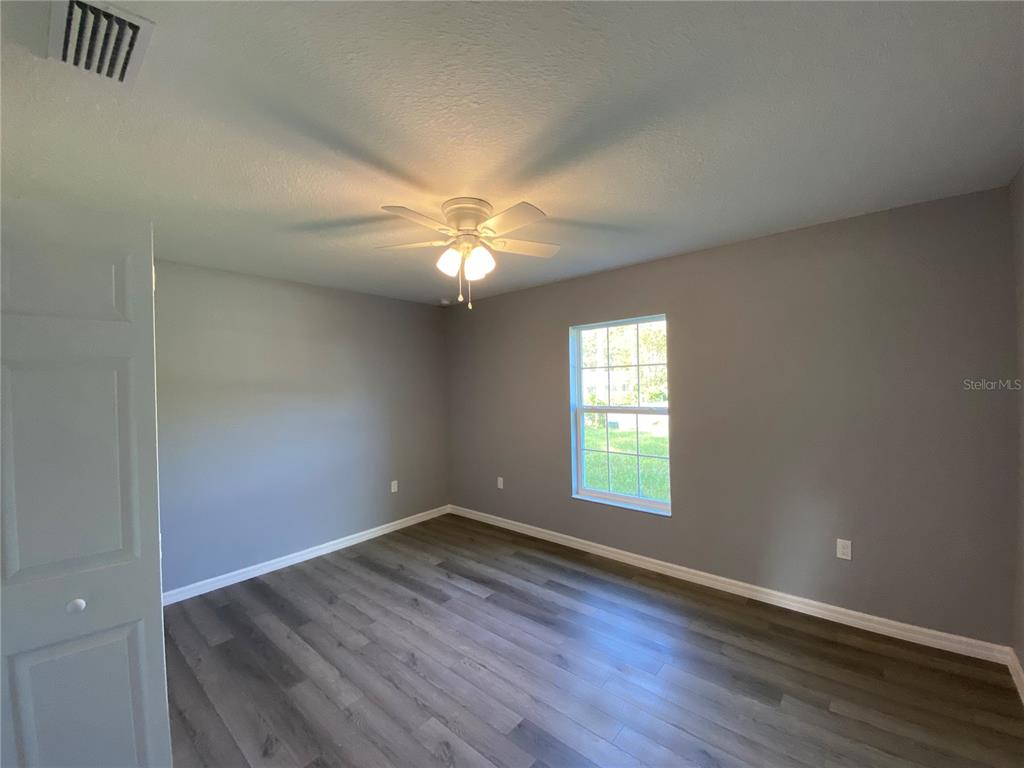 2827 Southwest 140th Loop Ocala, FL 34473 - Photo 24 of 29 an empty room with wooden floor and windows