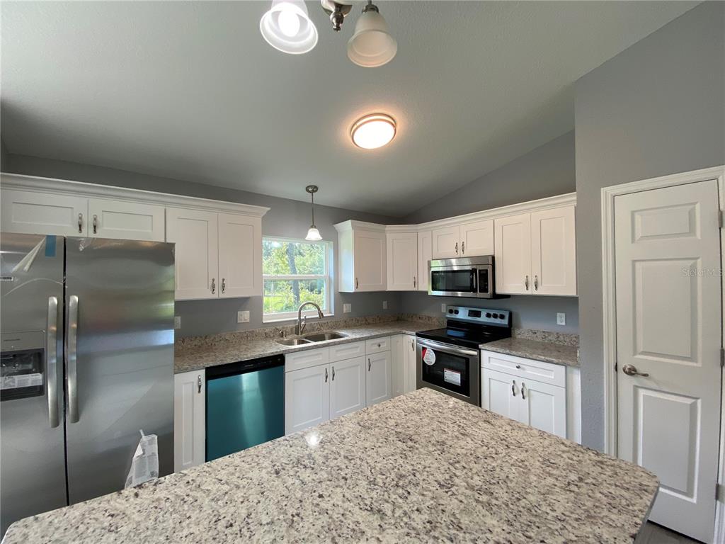 2827 Southwest 140th Loop Ocala, FL 34473 - Photo 8 of 29 a kitchen with stainless steel appliances granite countertop a sink stove refrigerator and cabinets